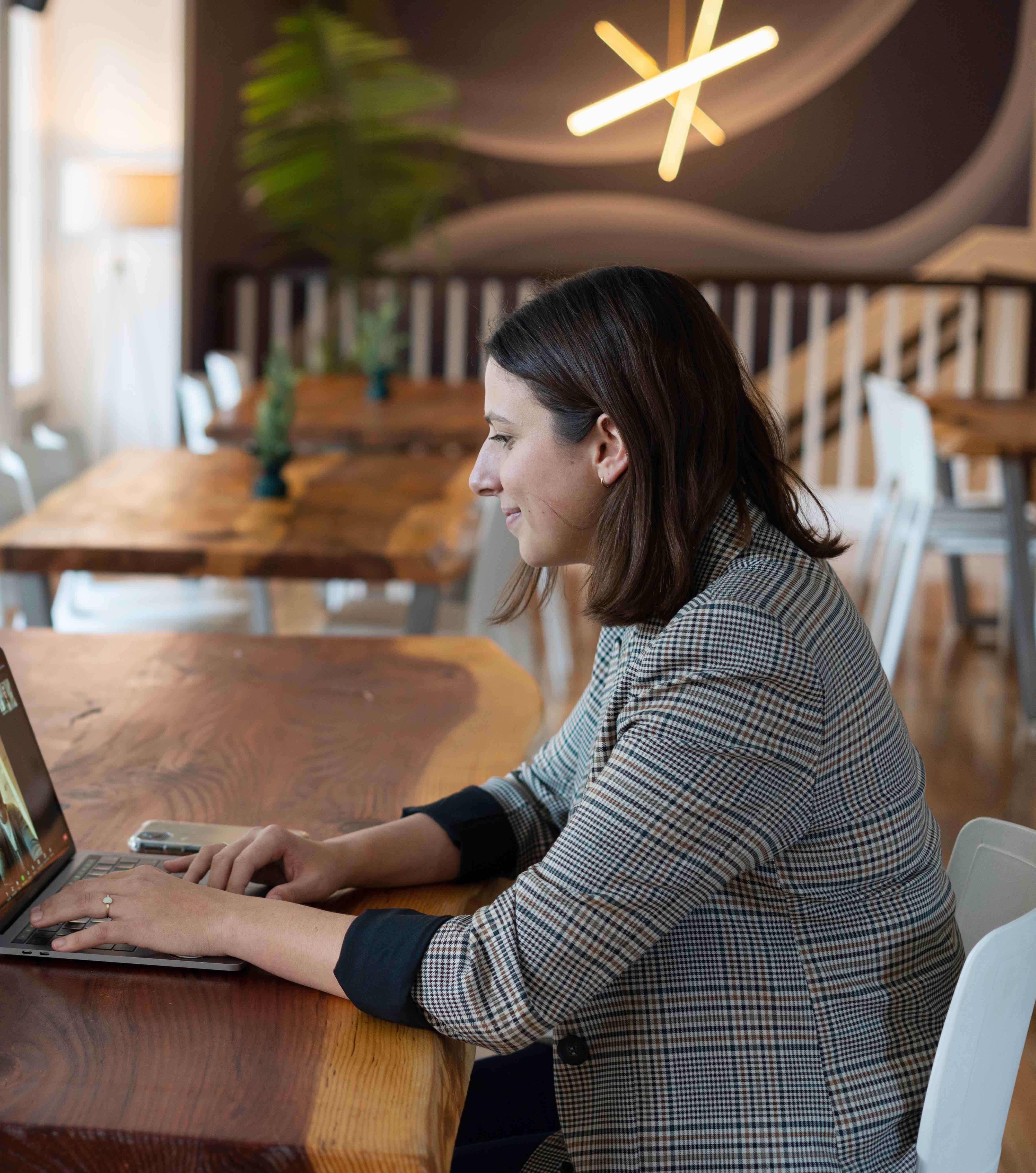 woman in a gray and white striped shirt using a silver macbook